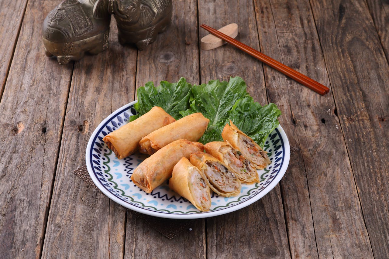 A plate of crispy spring rolls served with fresh lettuce on a wooden table.